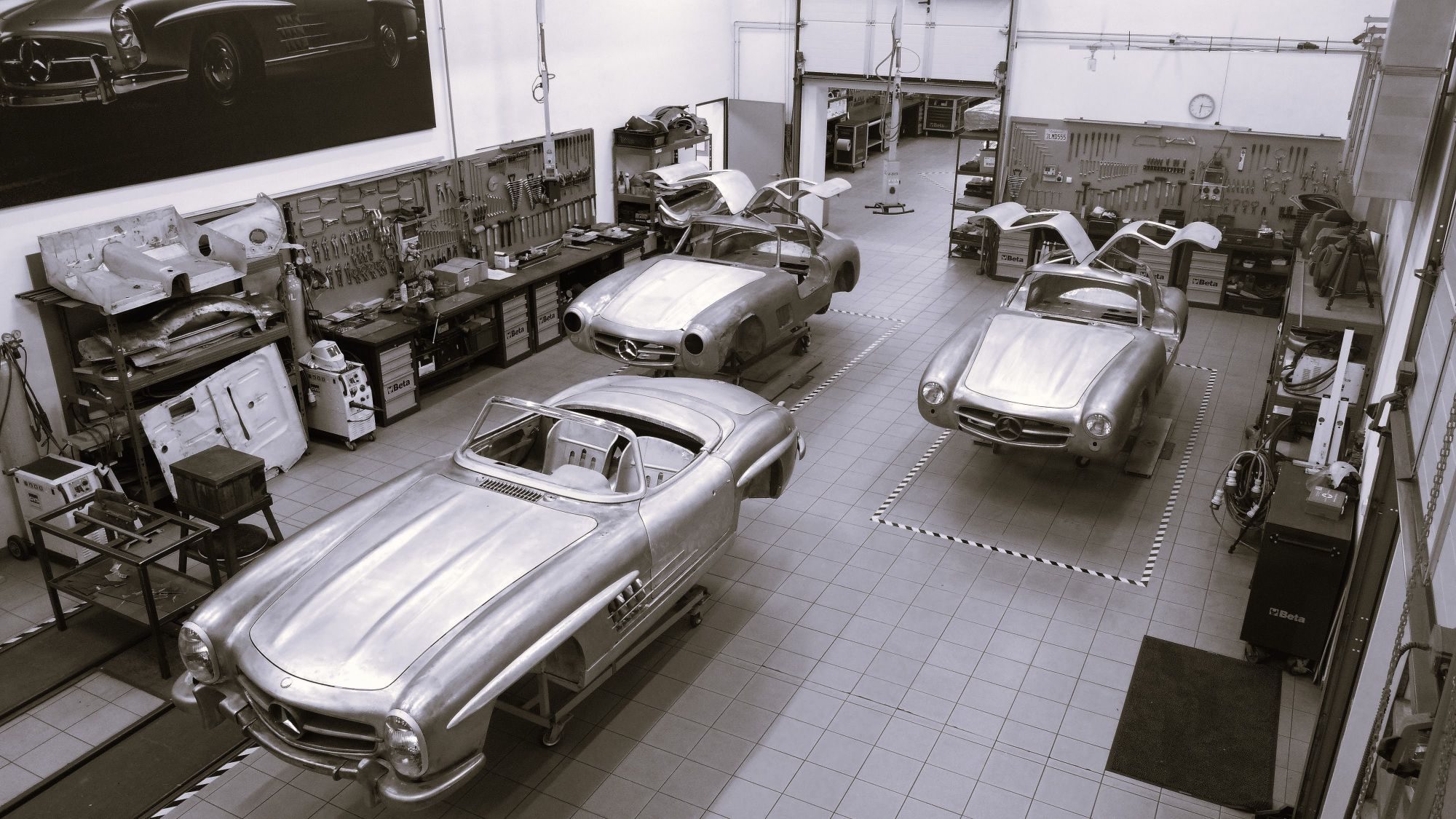 Black and white view from above of three 300 SL bodies in the workshop, two Gullwing coupés and a roadster