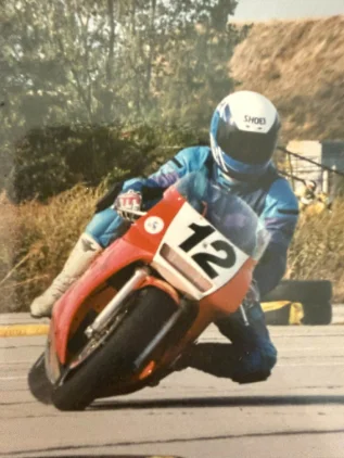 A racer in a blue helmet leaning a red racing motorcycle through a corner, number 12