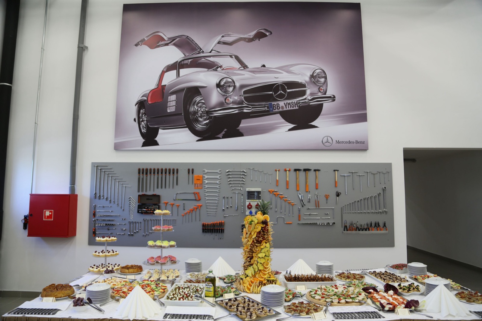 The reception buffet in the new hall, under a large photograph of a Mercedes-Benz 300 SL Gullwing and the tool wall