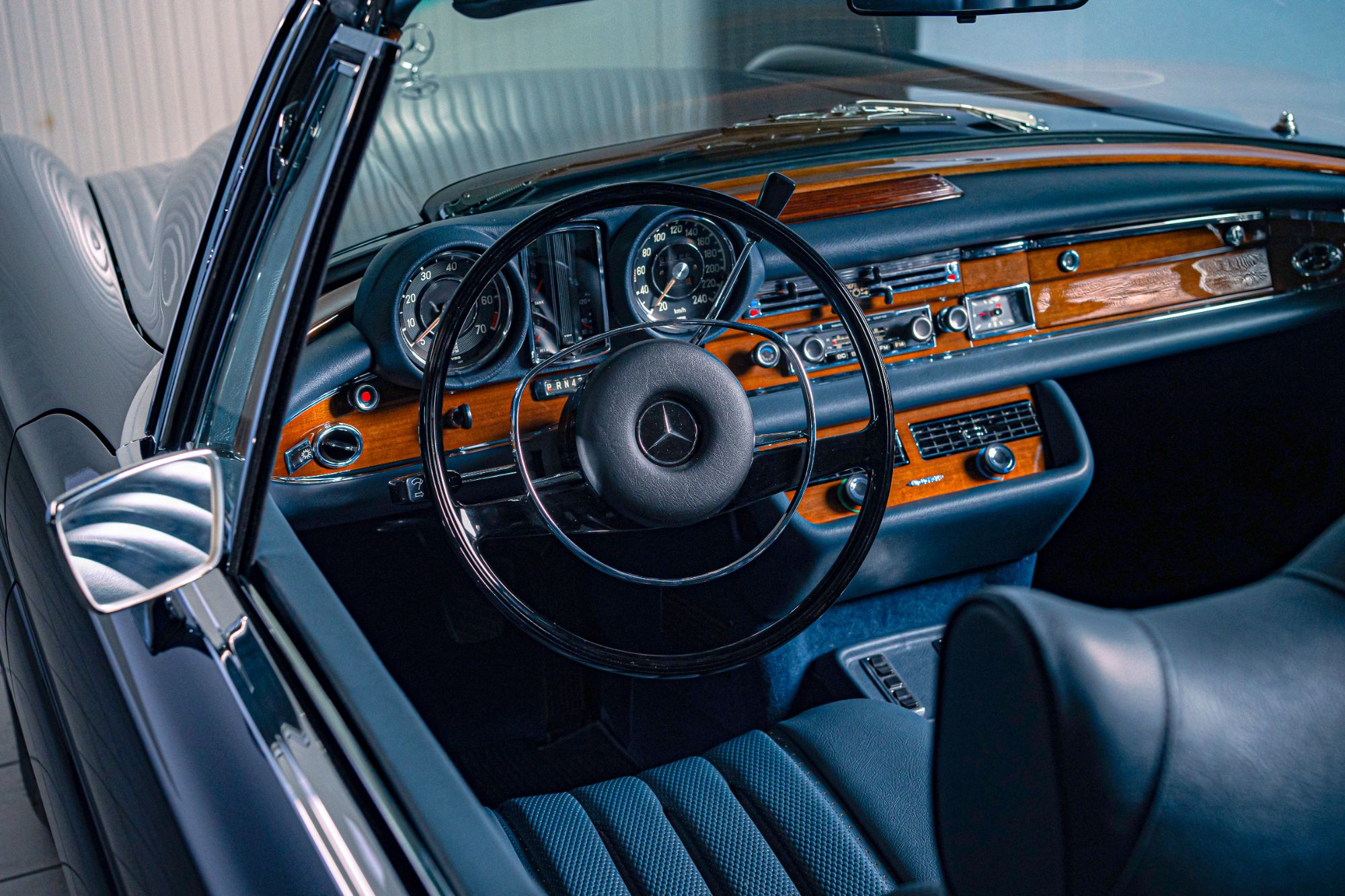 Wooden dashboard, steering wheel and blue leather seats of a restored W111 convertible