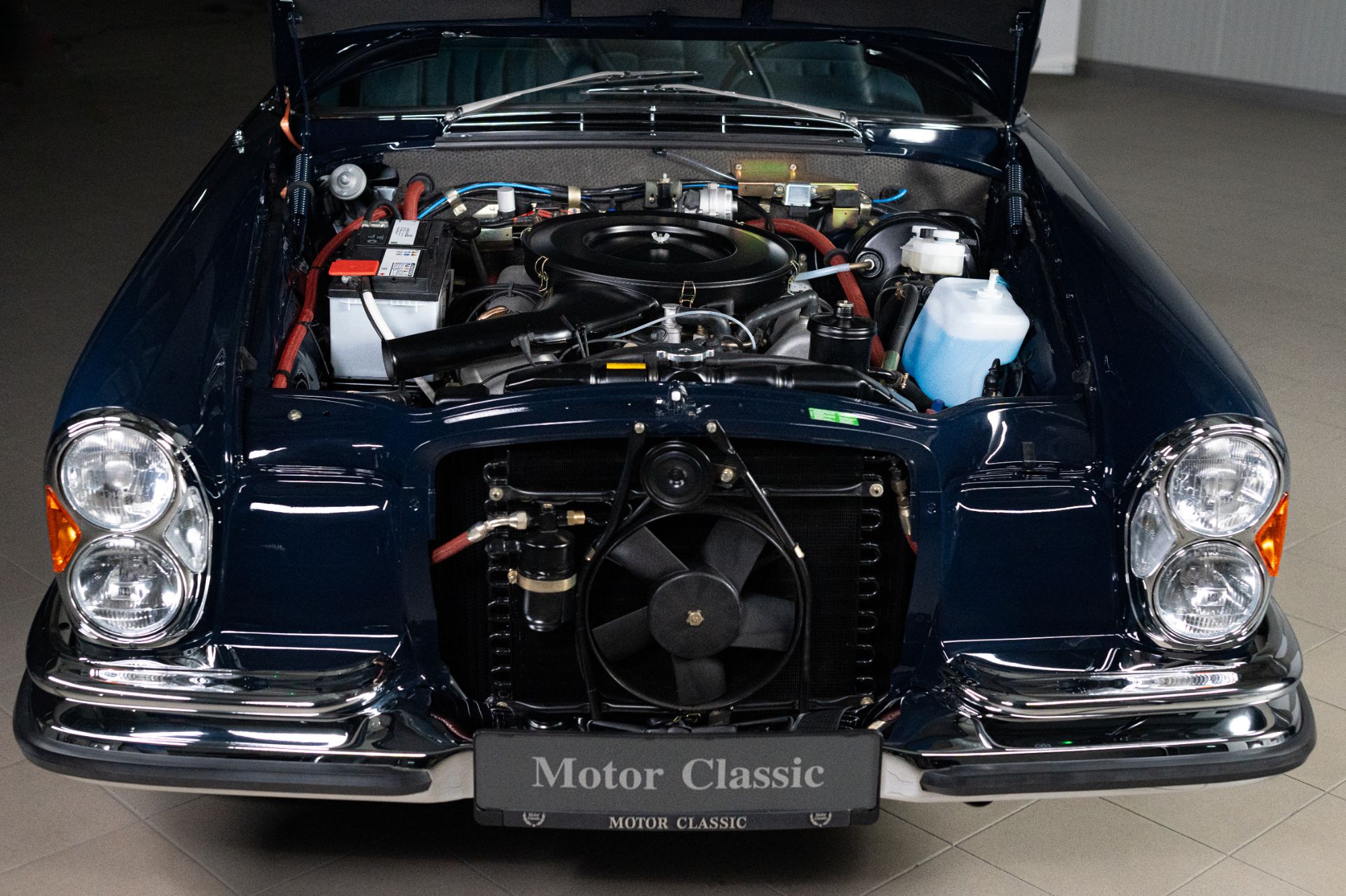 Open bonnet of a dark blue W111 showing the restored engine bay
